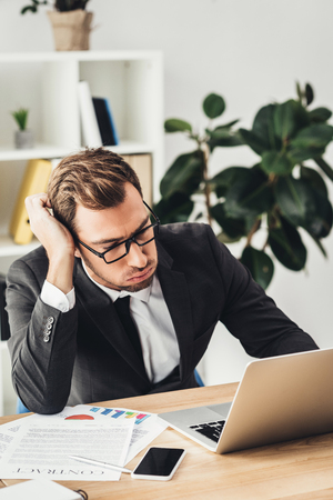 overworked businessman working with laptop in modern officeの写真素材
