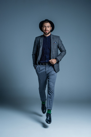 Young handsome man in suit and hat posing with hand in pocket and looking at cameraの写真素材