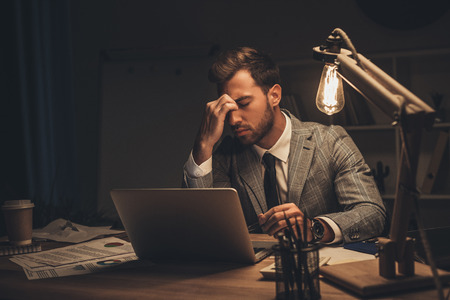 exhausted overworked businessman working with laptopの写真素材