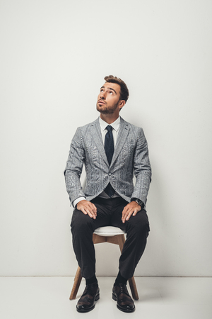 young handsome businessman in stylish suit sitting on chairの写真素材