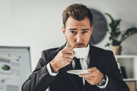 handsome young businessman drinking coffee at officeの写真素材