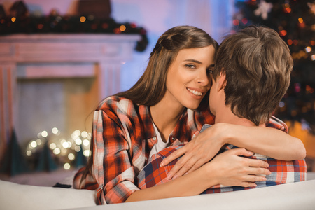selective focus of smiling woman hugging man in festive decorated room on christmas eveの写真素材