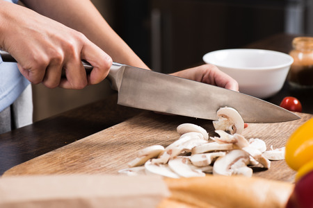 partial view of woman cutting mushrooms while cooking dinnerの写真素材
