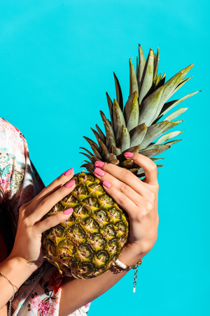 Cropped image of hippie woman holding pineapple in hands isolated on turquoise の写真素材