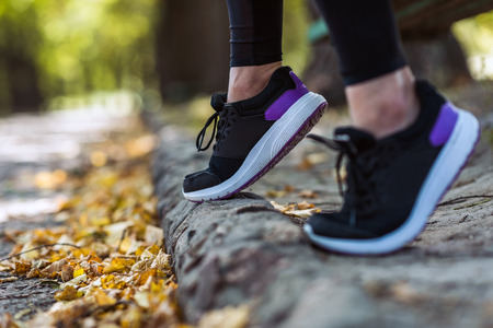cropped shot of woman in sneakers at autumn park