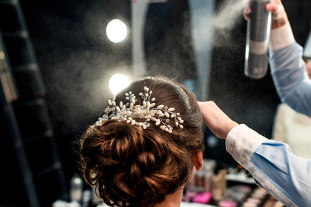 cropped shot of hairstylist fixating clients hairdo with hair sprayの写真素材