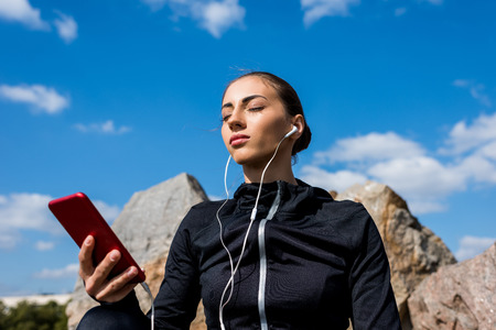 relaxed young woman listening music with earphones and smartphone outdoorsの写真素材
