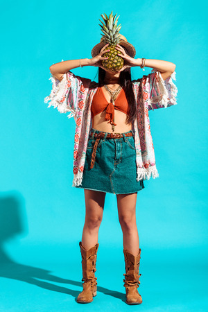 beautiful hippie girl covering face with pineappleの写真素材