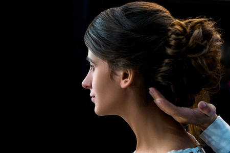 side view of woman getting hair done by hairstylist isolated on blackの写真素材
