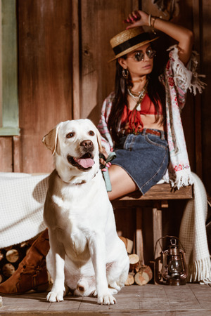 Attractive woman in boho style with a dog in a wooden houseの写真素材