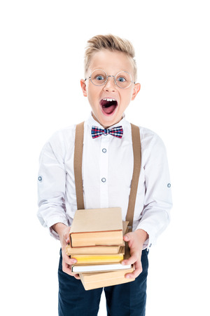 excited little boy in eyeglasses holding books isolated on whiteの写真素材