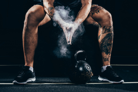 Cropped shot of young athletic sportsman applying talcum powder to his hands before exercising with kettlebellの写真素材