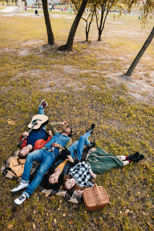high angle view of multicultural friends resting on blanket together in parkの写真素材