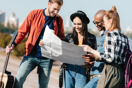 group of multicultural young friends choosing destination on map togetherの写真素材