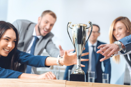 close-up shot of businesspeople trying to catch champion cupの写真素材