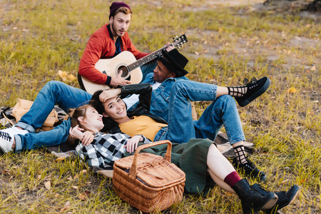 group of happy multicultural friends resting in park together