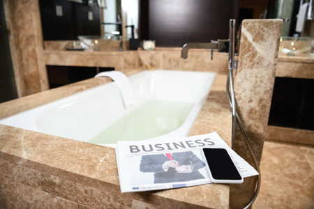 Hotel room bathtub with a business newspaper placed on itの写真素材