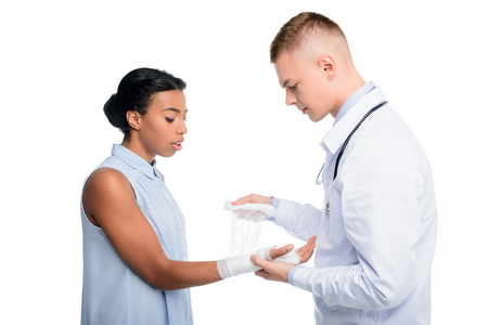 doctor puting bandage on womans hand, isolated on whiteの写真素材