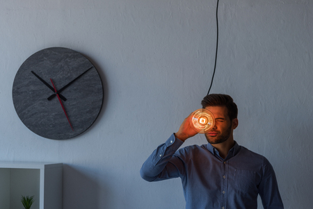 young businessman holding illuminated light bulb while standing in officeの写真素材