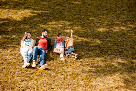 Happy family with children sitting on a grassy lawn in autumnの写真素材