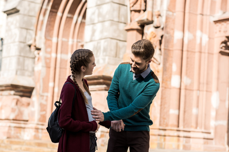 young man touching belly of pregnant wife while standing on street togetherの写真素材
