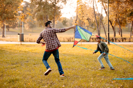 Father and son playing with a kite in an autumn parkの写真素材
