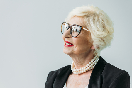 beautiful senior lady in pearl necklace and eyeglasses, isolated on greyの写真素材