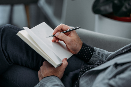 close-up partial view of businessman writing in notebookの写真素材