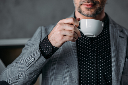 close-up partial view of stylish businessman holding cup of coffeeの写真素材
