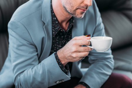 cropped shot of middle aged businessman holding cup of coffeeの写真素材
