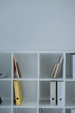 folders and books on white shelves in officeの写真素材