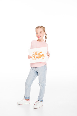 Cheerful child showing a card with text Merry Christmas, isolated on whiteの写真素材