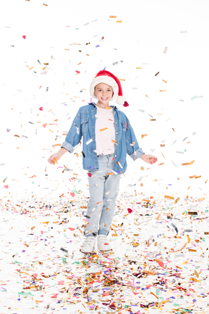 happy child in Santa hat with confetti on christmas, isolated on whiteの写真素材
