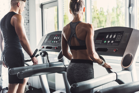 selective focus of couple exercising on treadmills in gym