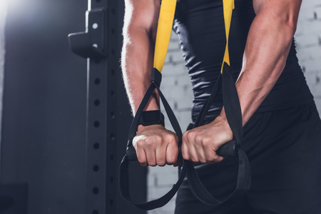 cropped shot of man exercising with trx gym equipment