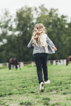 back view of blonde child running at countryside の写真素材