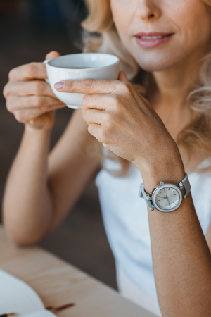 cropped shot of smiling woman holding cup of coffeeの写真素材