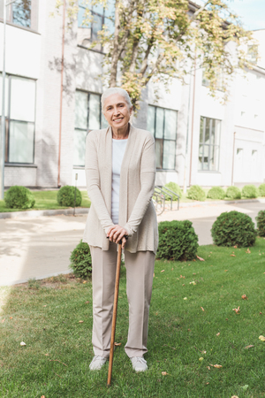 happy senior woman with walking cane smiling at cameraの写真素材