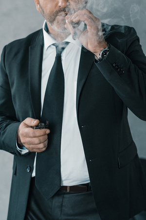 cropped shot of mature businessman smoking cigarの写真素材