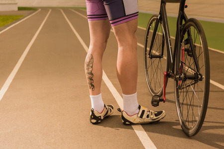 partial view of cyclist standing near bicycle on cycle race track