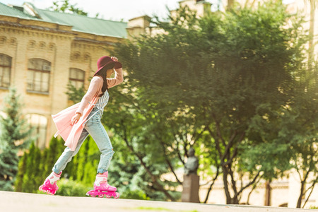 side view of stylish young woman riding roller skates in park 