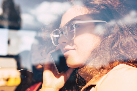 portrait of young woman talking on smartphone in public transportの写真素材