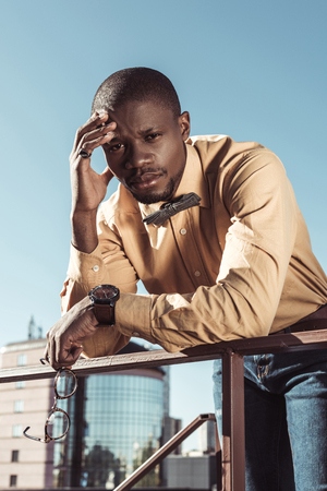 Handsome african american man leaning on guradrails and looking at cameraの写真素材