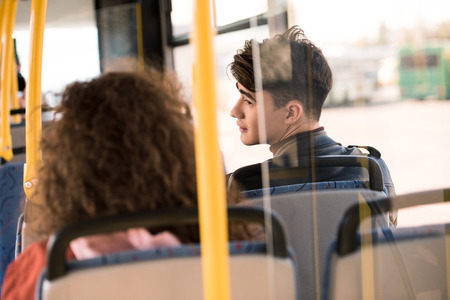 back view of handsome young man looking over shoulder at girl in busの写真素材