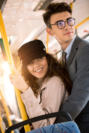 smiling young couple standing together and looking away in busの写真素材