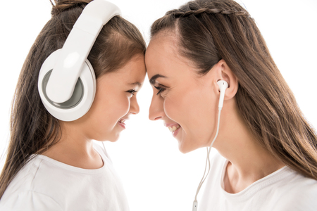 mother and daughter listening music with headphones and earphones, isolated on whiteの写真素材