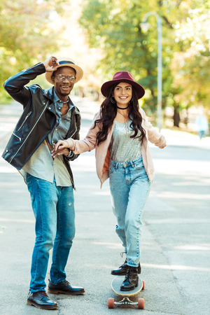lovely Boyfriend helping his girlfriend to skate on a longboard in the park の写真素材