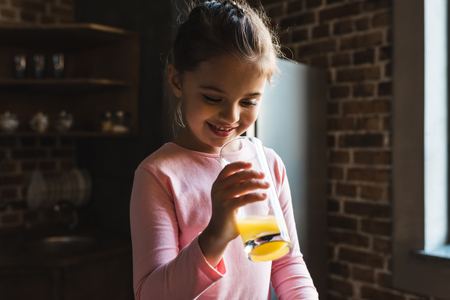 smiling little child drinking orange juiceの写真素材