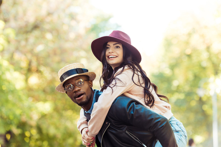 boyfriend giving piggyback to his girlfriend while walking in the park の写真素材