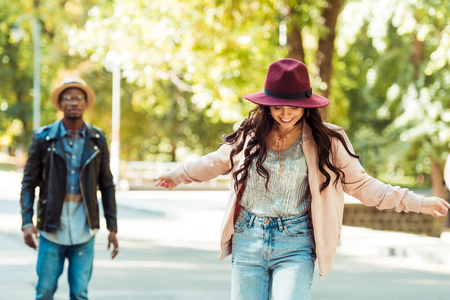 Boyfriend looking at his girlfriend skateboarding in a parkの写真素材